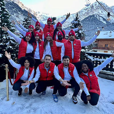 Kinder und Team in roten Westen posieren im Schnee, Berge im Hintergrund