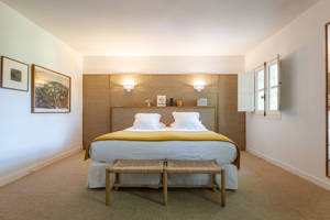 A well-organized bedroom features a cozy bed and two portraits mounted on the left wall.