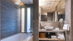 A clicked photo of a neat bathroom shows arranged bathing essentials and a mirror above.