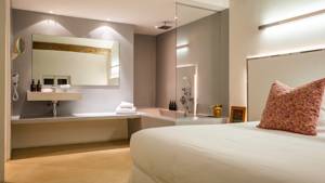 A properly arranged bedroom featuring a cozy bed and a wall basin with large mirror.