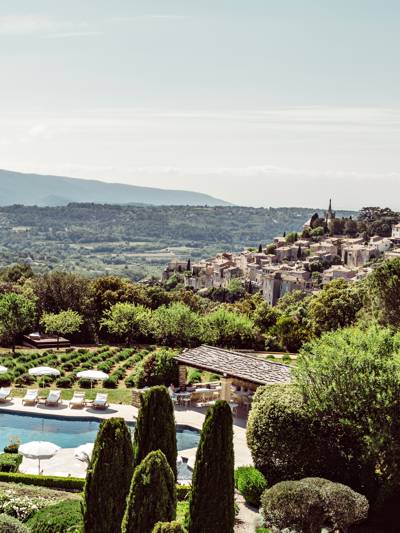 Piscine et jardins de l'hôtel Capelongue avec le village de Bonnieux et la vallée du Luberon en arrière-plan