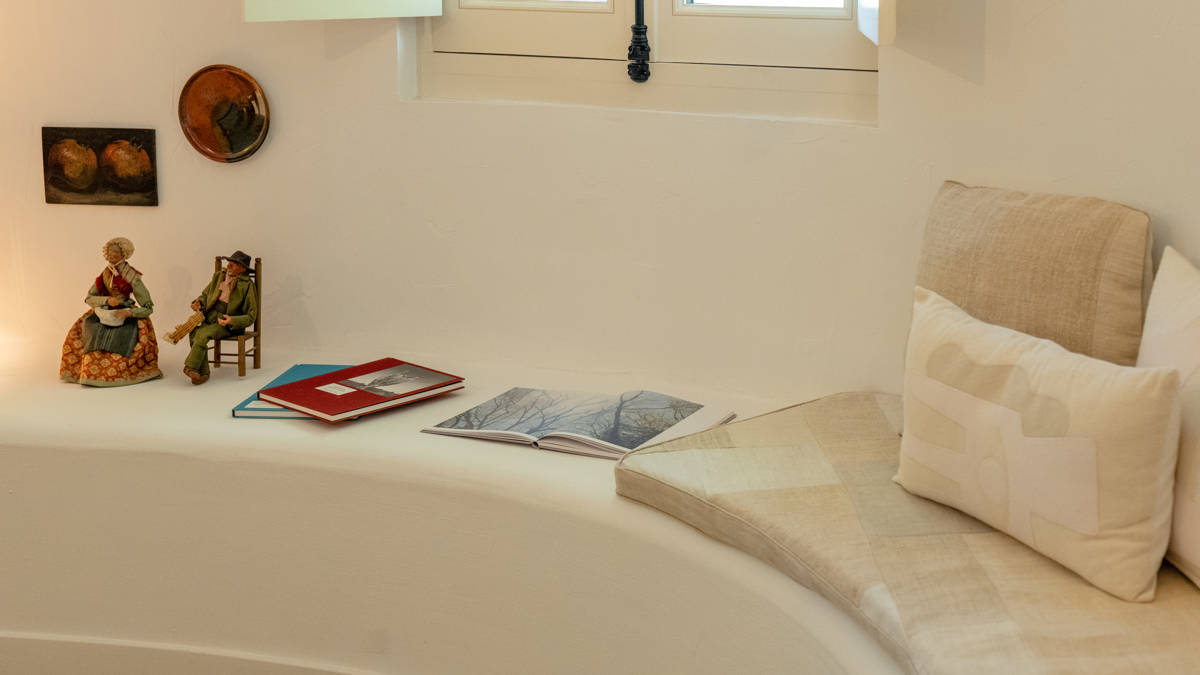 A designer toy along with some notebooks is placed right beside the cozy sofa.