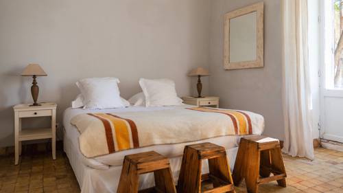 A tidy bedroom featuring a cozy bed, two side tables with lamps, and three chairs.