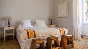A tidy bedroom featuring a cozy bed, two side tables with lamps, and three chairs.