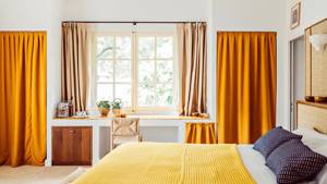 A well-organized bedroom features a cozy bed and a chair by the table near the window.