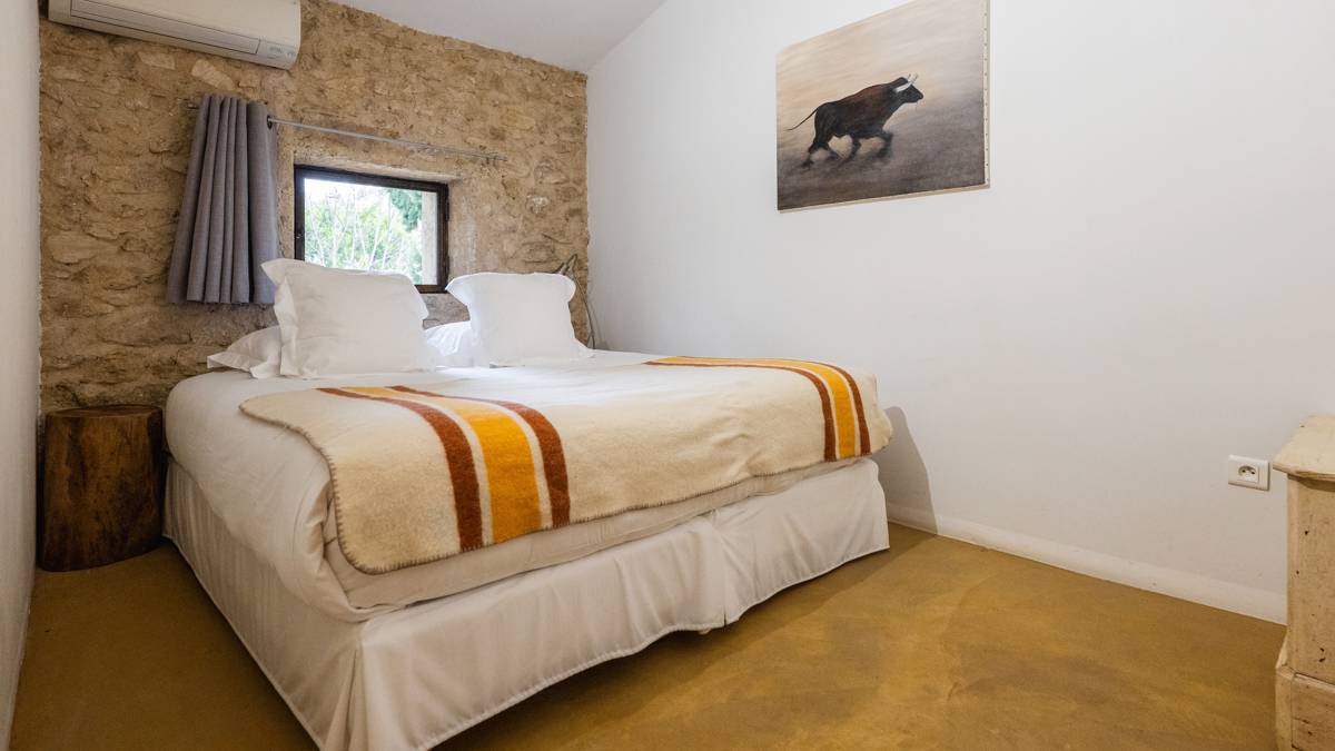 A tidy bedroom features a comfortable bed with a portrait mounted on the right wall.