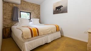 A tidy bedroom features a comfortable bed with a portrait mounted on the right wall.
