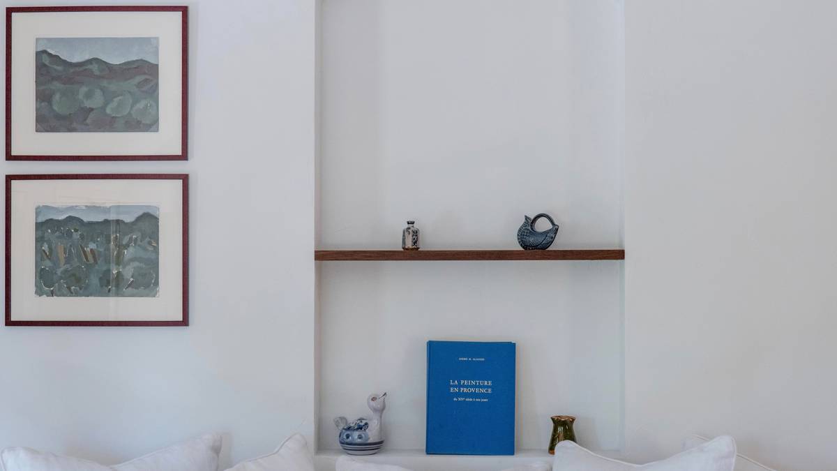 Some decorative items and a notebook are on the wall shelves, with two portraits beside.