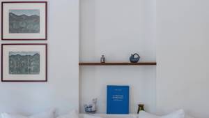 Some decorative items and a notebook are on the wall shelves, with two portraits beside.