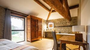 Properly arranged bedroom with cozy bed, table and chair, and wooden cupboard near glass door.