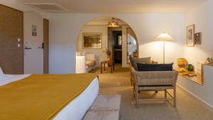 A properly organized bedroom features a cozy bed, with a set of chairs and table in front.