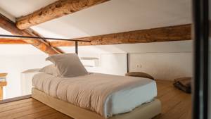 A cozy bed is placed upstairs with two small sitting bags to its right.