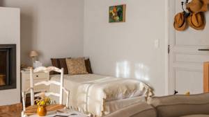 A tidy bedroom features a cozy bed, a nearby chair, and a portrait above.