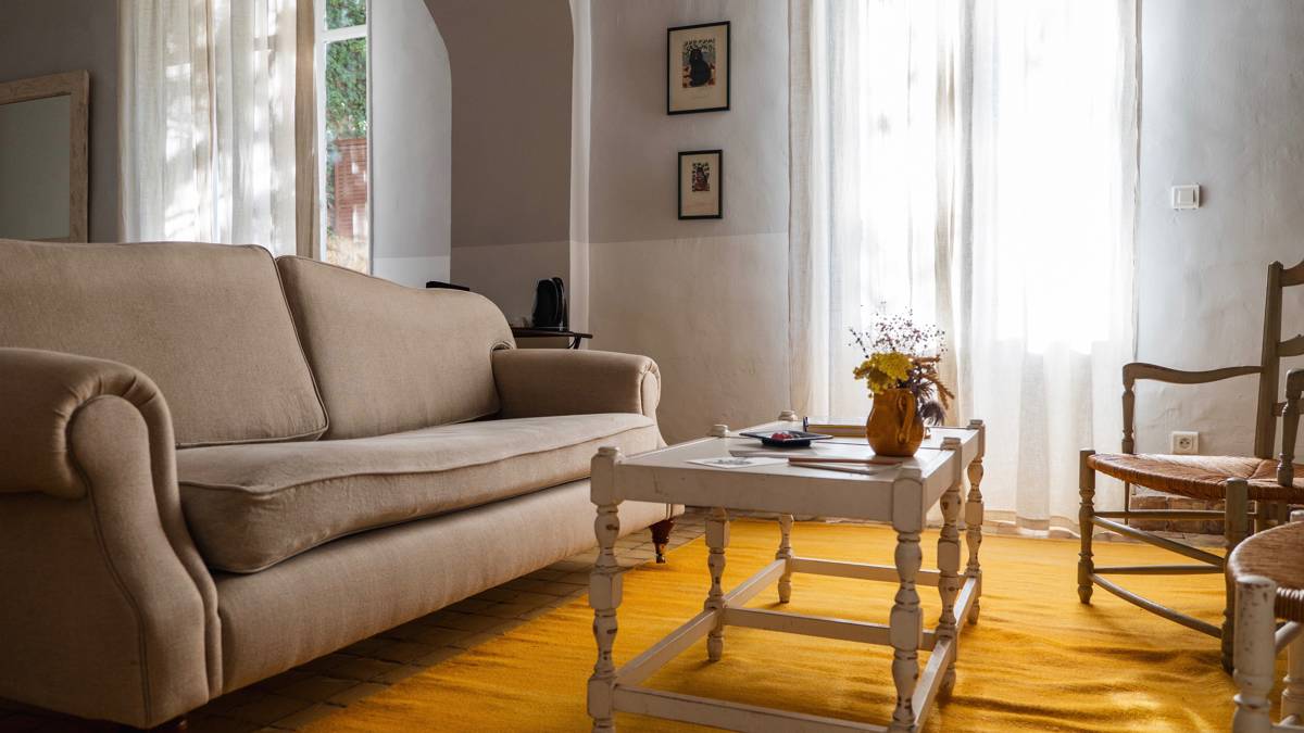 A tidy living space featuring a cozy sofa set near curtained window and two portraits.