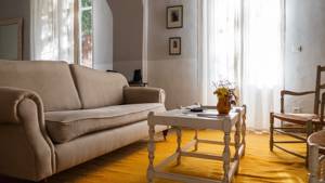 A tidy living space featuring a cozy sofa set near curtained window and two portraits.