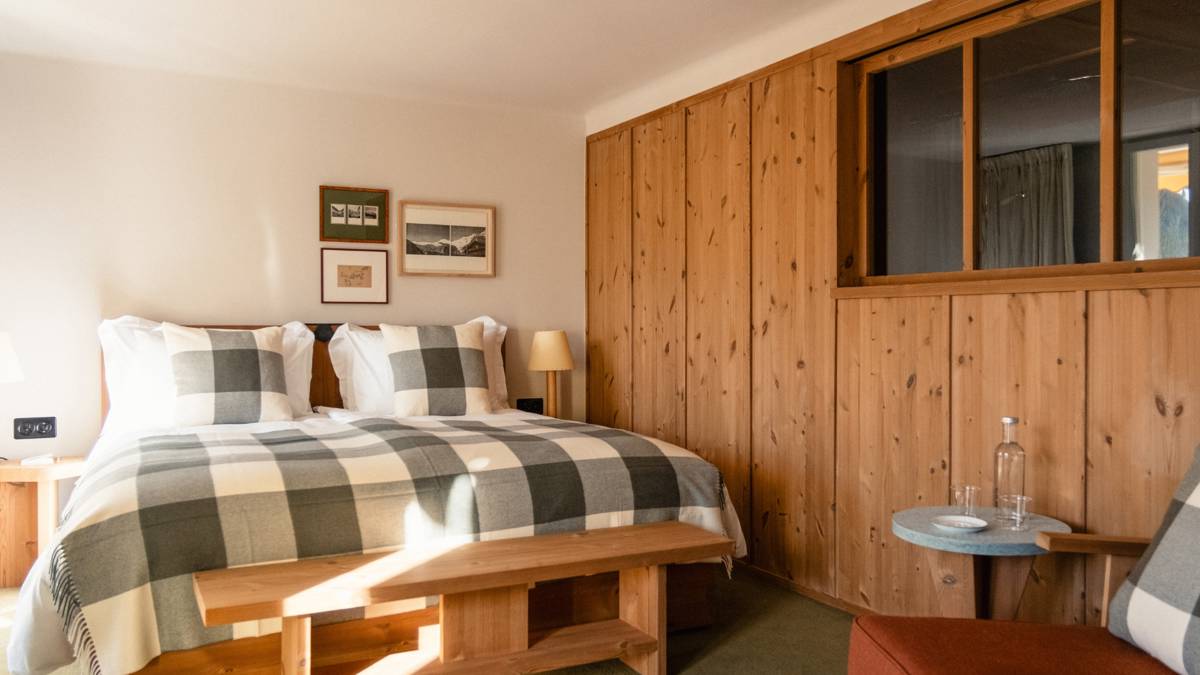 A well-organized bedroom features a cozy bed, two side tables with lamps, and portraits mounted above.