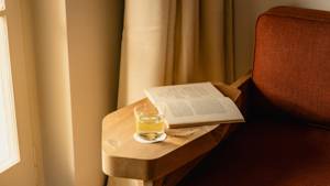A cocktail glass is placed on the armrest of the cozy sofa.