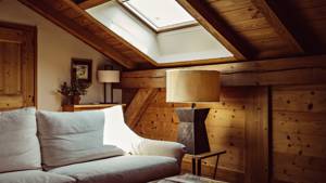 An organized living space features a couch, a side table with lamp, and a portrait above.