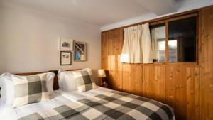 A well-organized bedroom features a cozy bed, side table with a lamp, and portraits above.
