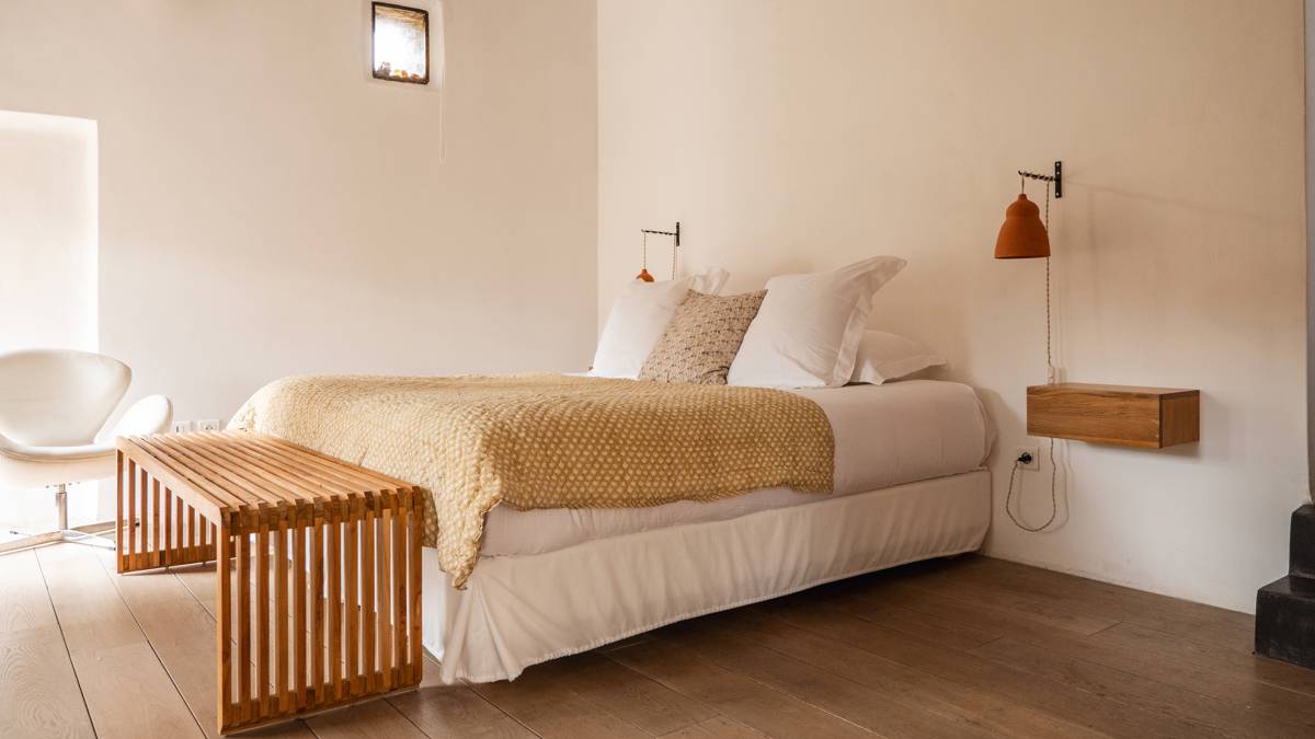 An organized bedroom features a cozy bed, a nearby chair, and hanging lamps on both sides.