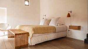 An organized bedroom features a cozy bed, a nearby chair, and hanging lamps on both sides.