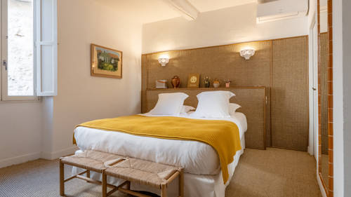 A well-organized bedroom features a cozy bed with a portrait mounted on the left wall.