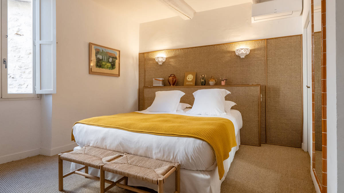 A well-organized bedroom features a cozy bed with a portrait mounted on the left wall.