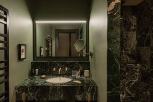 Salle de bains du Fitz Roy à Val Thorens, vasque en marbre vert, robinetterie laiton et miroir rétroéclairé