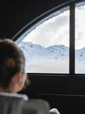 Person loking through a car window to the snow mountain