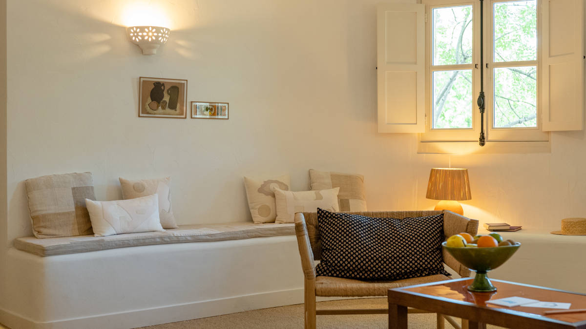 A cozy chair is placed near a table holding a fruit basket.