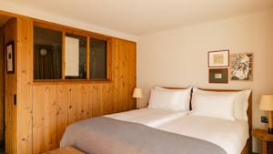 A bedroom features a cozy bed, two side tables with lamps, and portraits above.