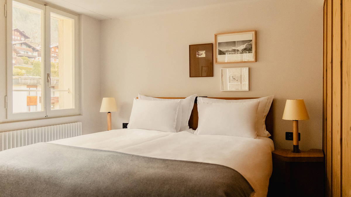 A well-organized bedroom features a cozy bed with two side tables and portraits above.