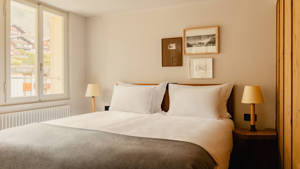 A well-organized bedroom features a cozy bed with two side tables and portraits above.