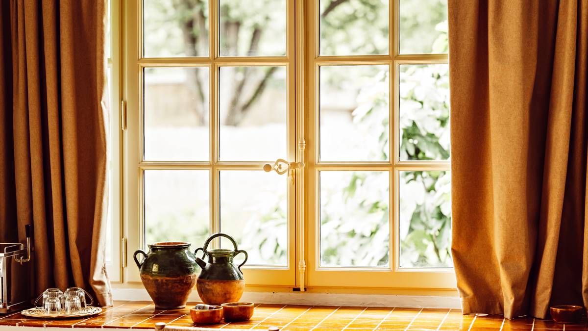 A uniquely designed vase is placed near the glass window, offering a beautiful lawn view.