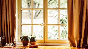 A uniquely designed vase is placed near the glass window, offering a beautiful lawn view.