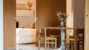 A well-organized dining area features a round table with chairs, flower vase, and wine bottle.