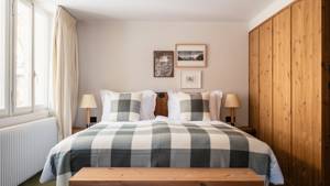 A well-organized bedroom features a cozy bed, two side tables with lamps, and mounted portraits.