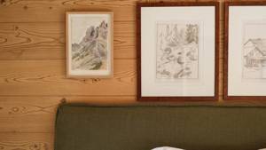 Three portraits are mounted on the wooden-finished wall just above the bed’s headboard.