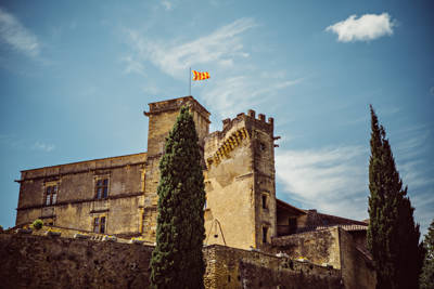 Château de Lourmarin, premier château Renaissance de Provence, flanqué de cyprès sous un ciel bleu