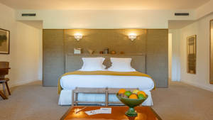 A well-organized bedroom features a cozy bed and a table in front holding a fruit basket.