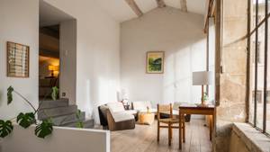 An organized living space features a cozy sofa, coffee table, nearby chair with lamp, and portrait.